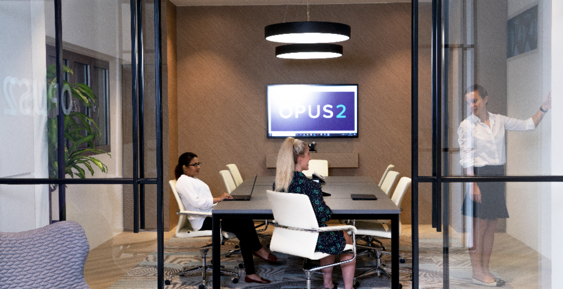 Opus 2 modern meeting space with three individuals brainstorming and writing on a white board